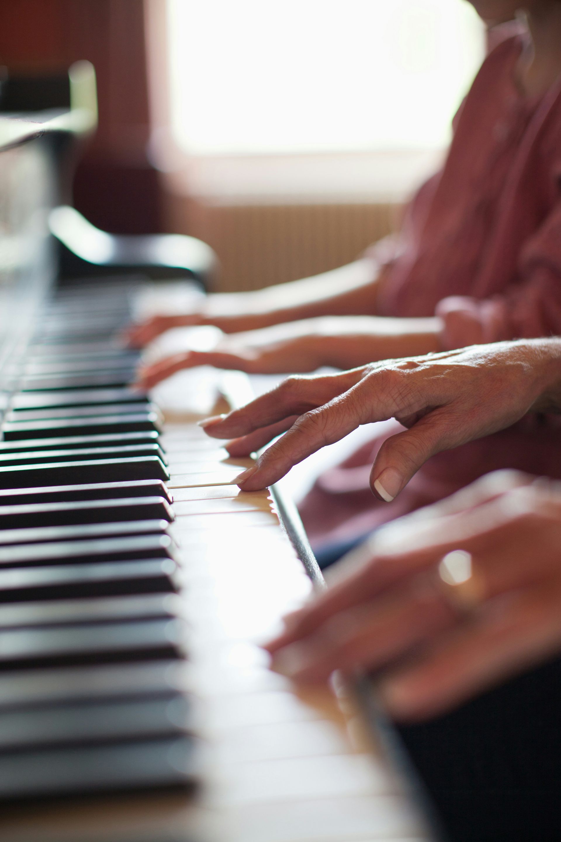 People of different generations playing a piano together